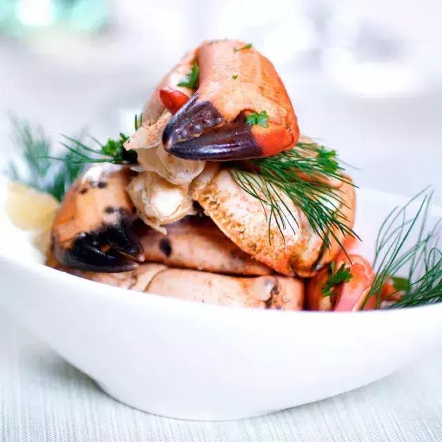 Les pattes de crabe sont empilées dans un bol blanc et saupoudrées d'aneth frais.